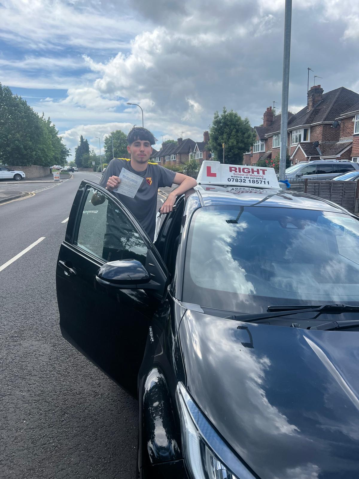 Happy student holding pass certificate beside Right School of Motoring vehicle