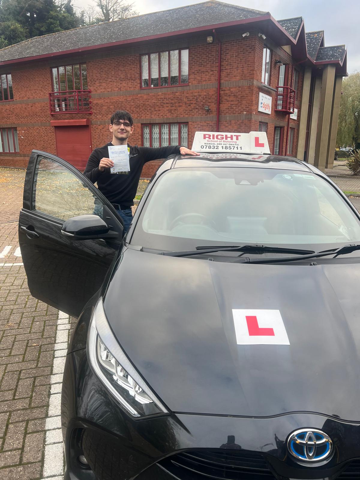 Happy student with pass certificate beside driving school car